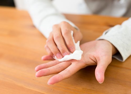 Woman wiping away excessive sweat on hands